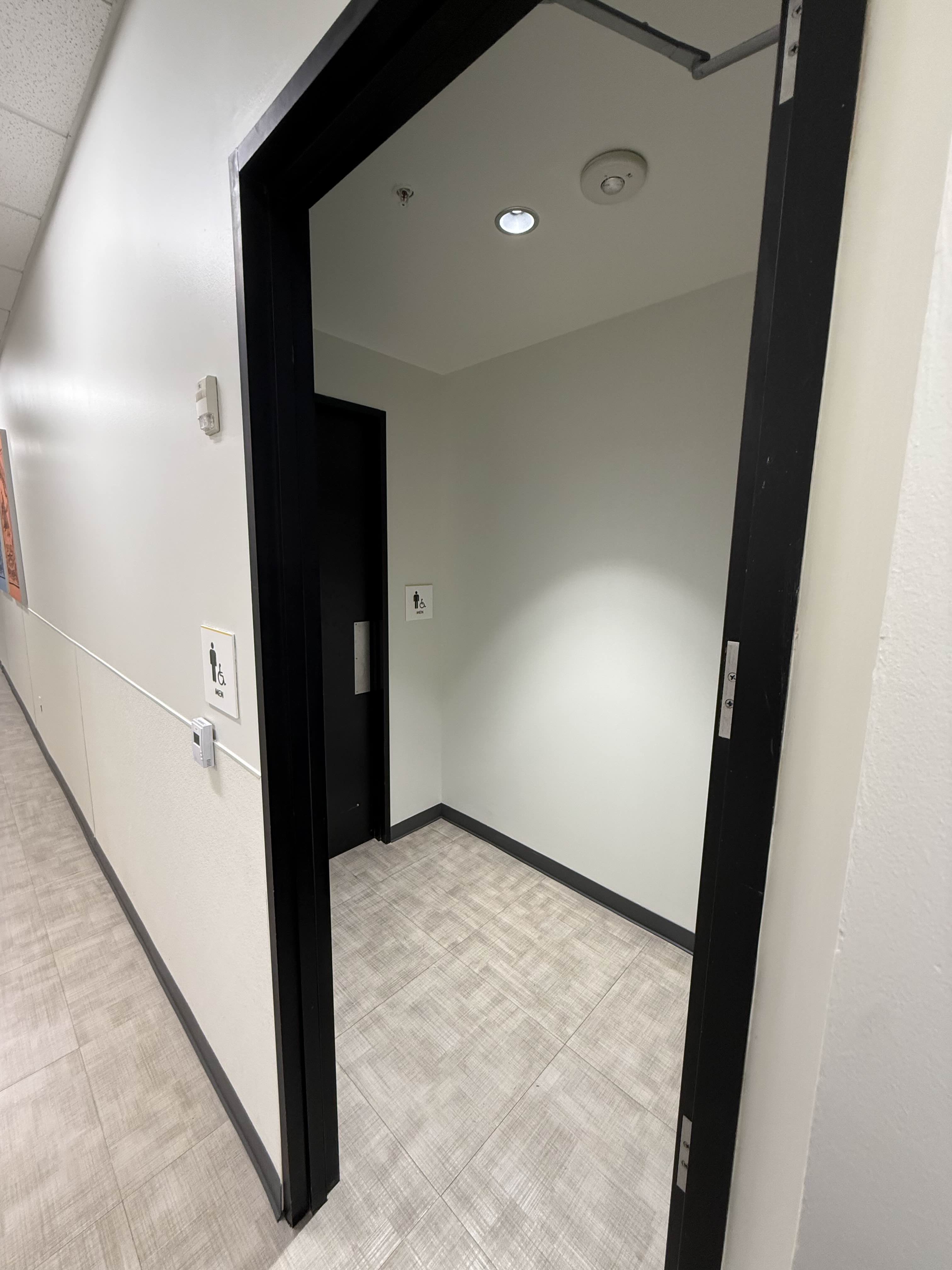Hallway entrance to restroom area before access control — door closer visible but no mag lock or reader