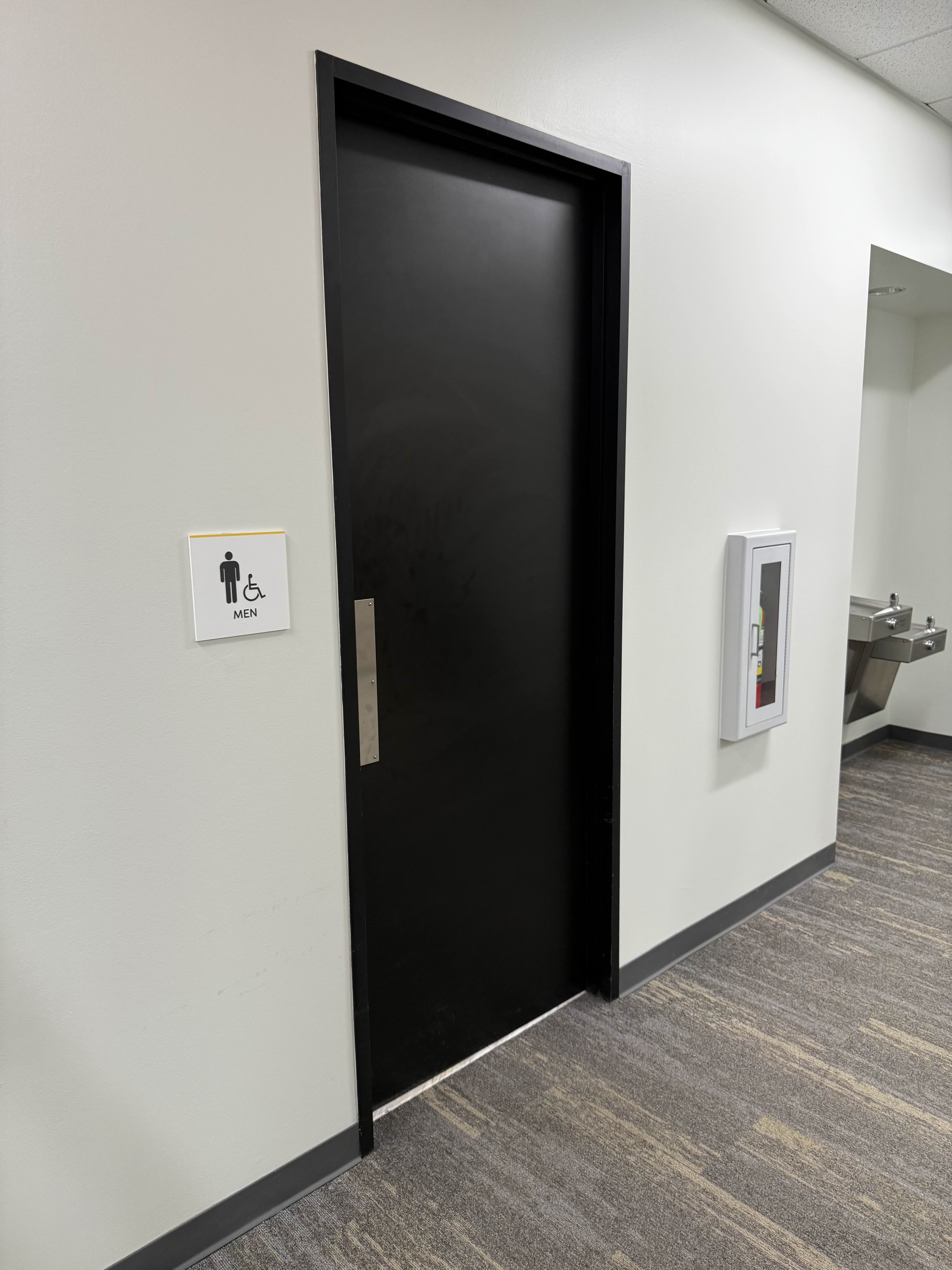 Men's restroom door before access control installation — no card reader, no mag lock, just a push plate
