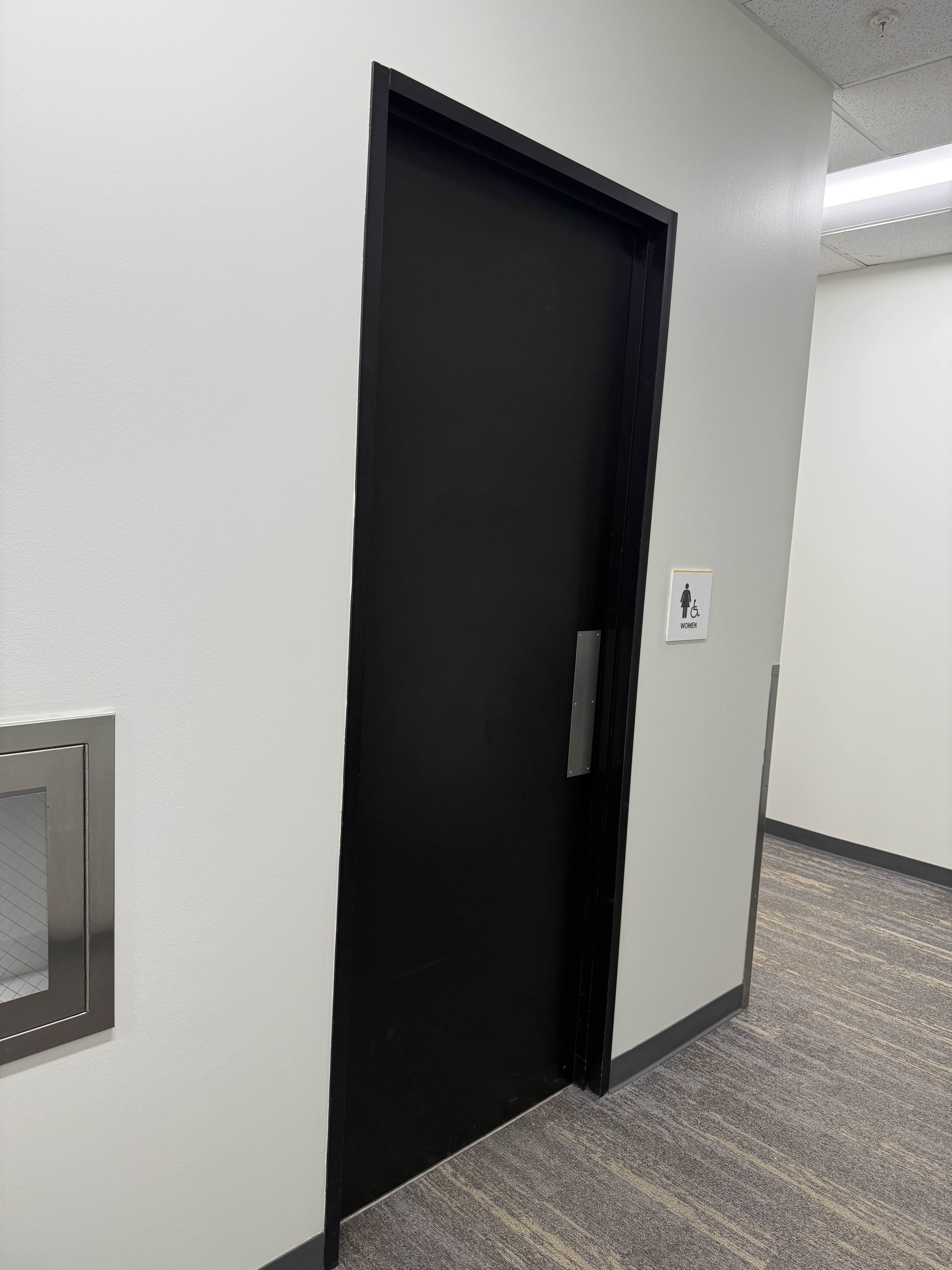 Women's restroom door from wider angle before access control — plain commercial door