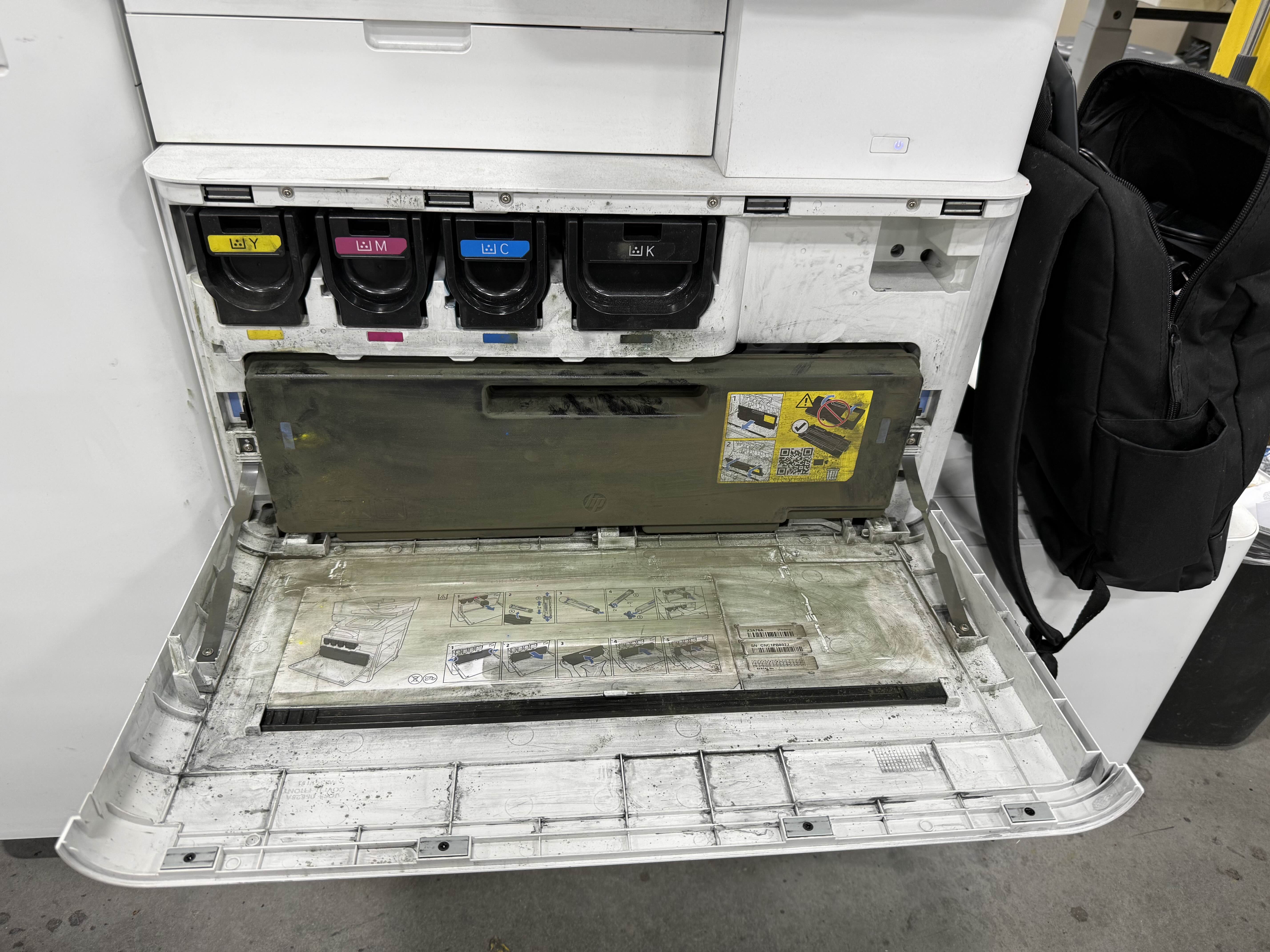 HP Enterprise MFP ink cartridge bay open showing YMCK cartridges during on-site maintenance