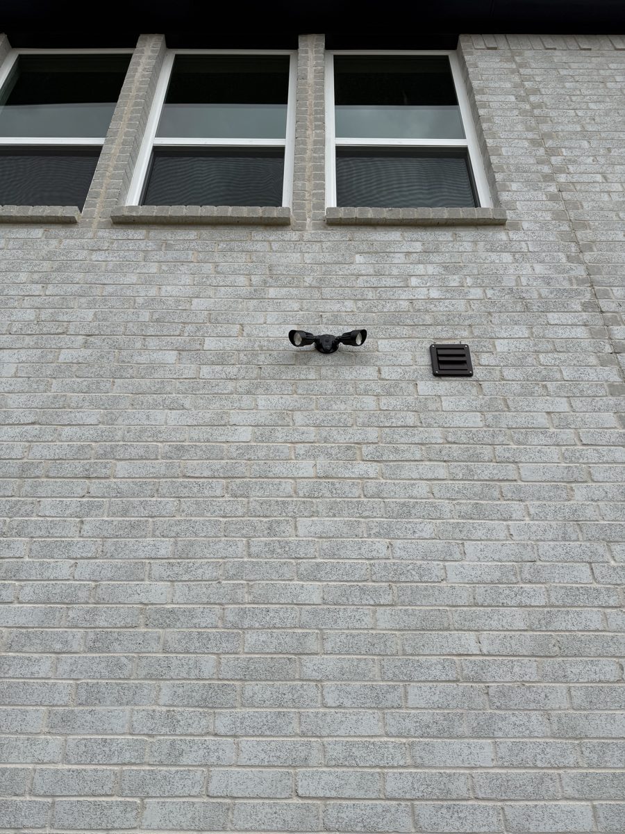 Security camera mounted high on second-story brick wall of a DFW home