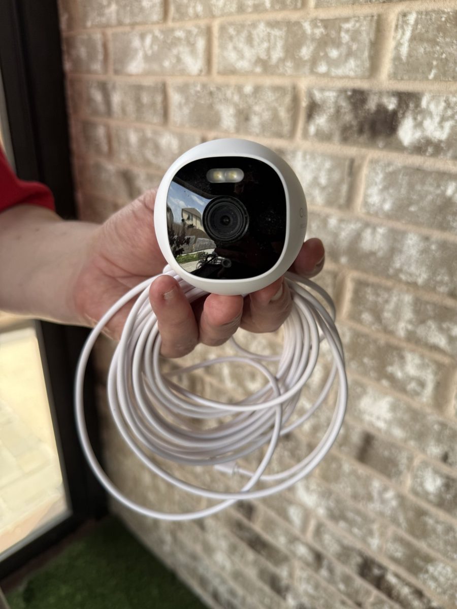 Wired outdoor security camera with spotlight and cable before mounting on brick exterior
