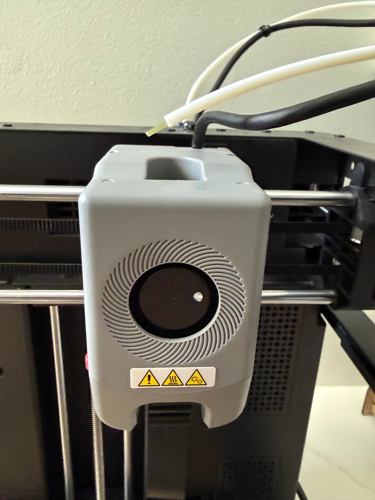 Close-up of a 3D printer extruder head during repair, showing the hotend and feed mechanism