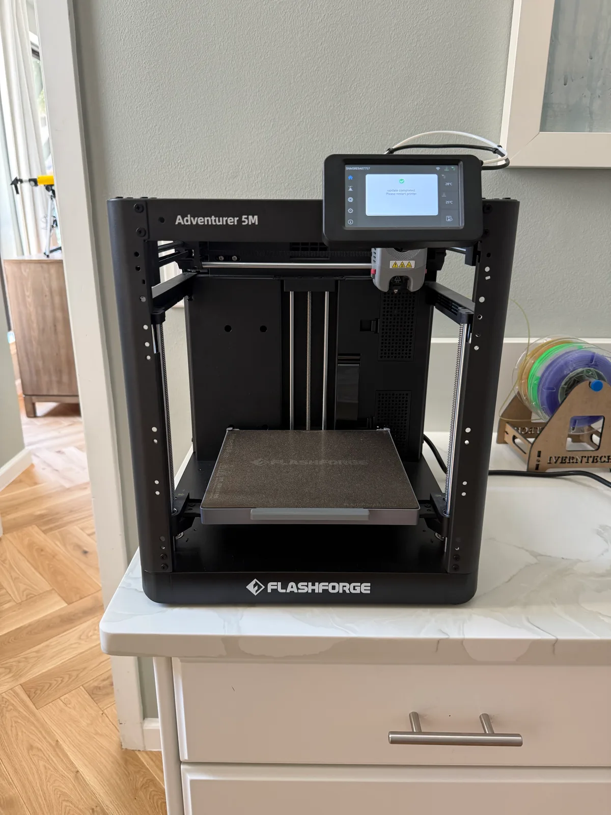 FlashForge Adventurer 5M 3D printer, front view showing touchscreen and filament spool, used for our in-house custom printing service